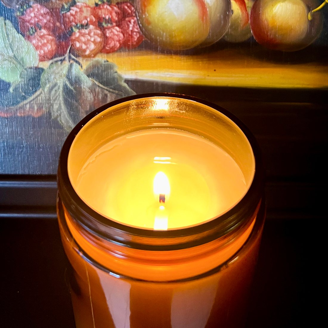 A candle burning in an amber jar.