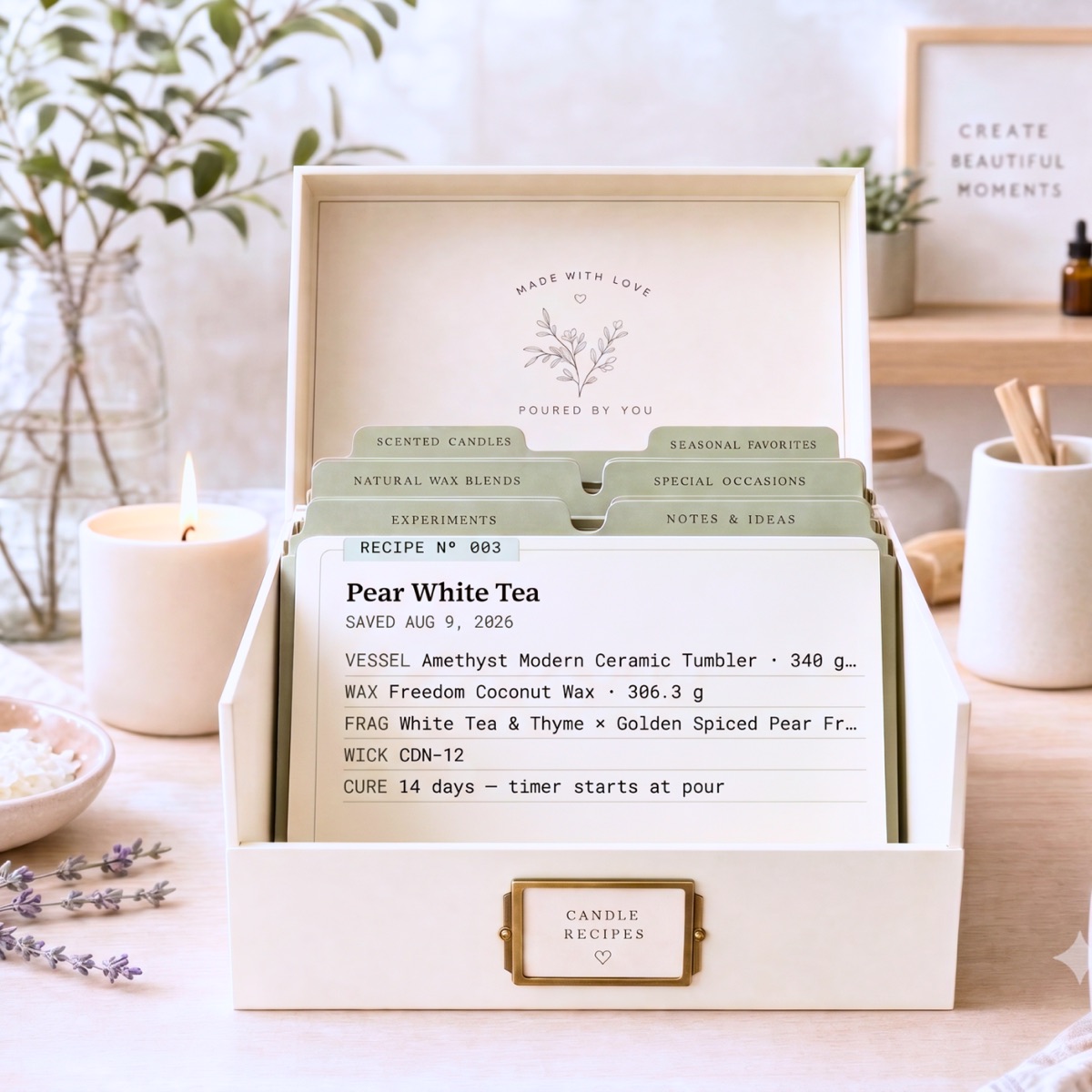 A recipe box of candle recipe cards on a studio table beside a lit candle.